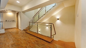 Un interior moderno con piso de madera, escalera con barandilla de vidrio y una zona de cocina con armarios y pileta.