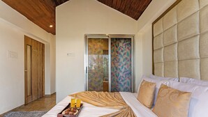 Un dormitorio con cama, una bandeja con muffins y jugo, una puerta de madera y un ventanal corredero con diseño de hojas.