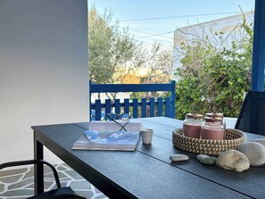 A balcony with a table, a chair, a book, a pair of glasses, a basket, and jars. - Origins III | Modern Seaside Studio in Piso Livadi (Piso Livadi Paros)