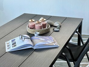 Ein Holztisch mit einem Buch, Brillen, Kerzen und einem gewebten Korb.