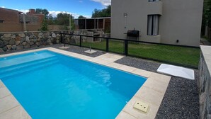 Une piscine avec un mur en pierre et un bâtiment moderne en arrière-plan.