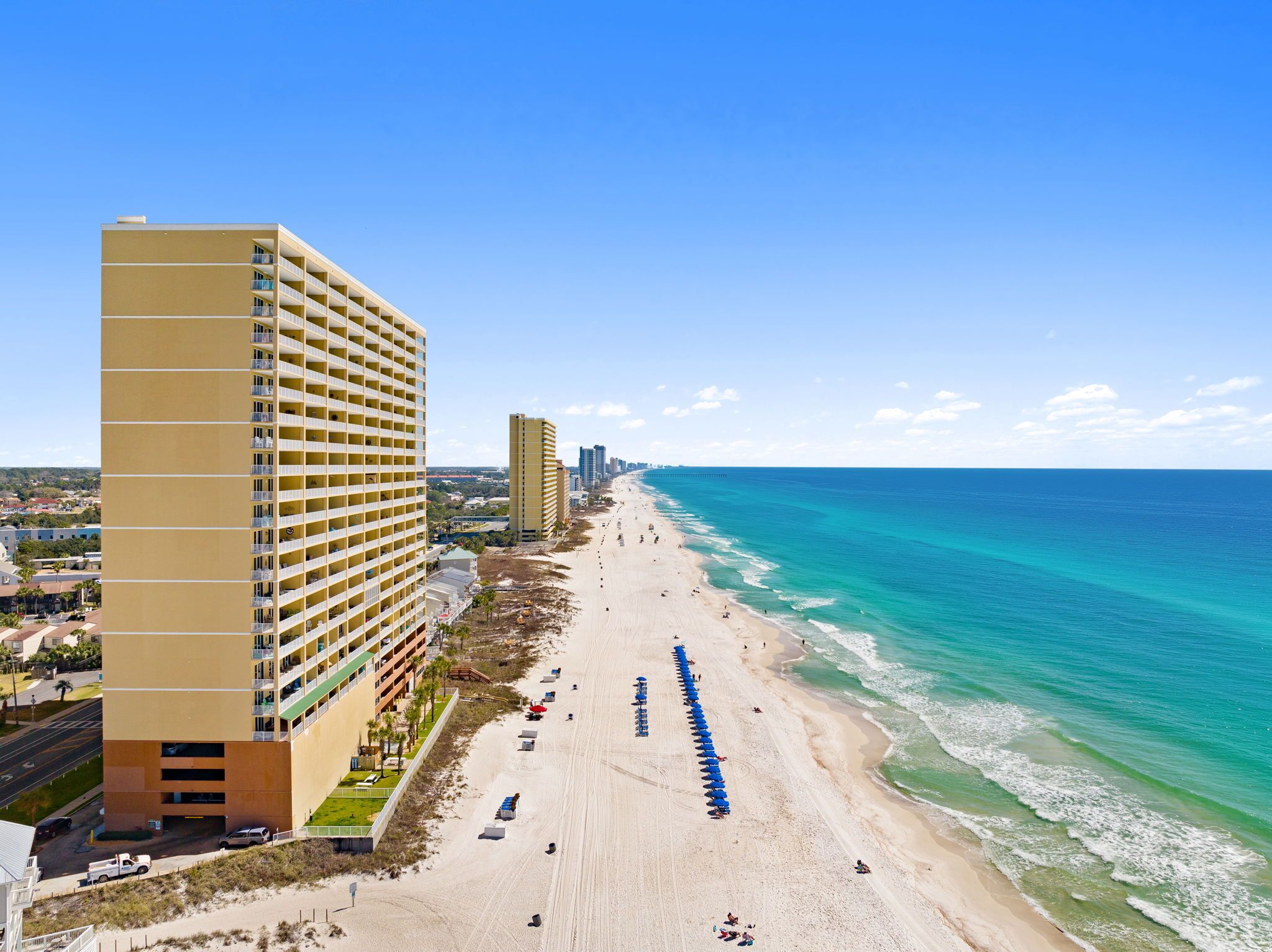 Un hotel frente a la playa con una estructura de gran altura, una playa de arena y vistas al océano.