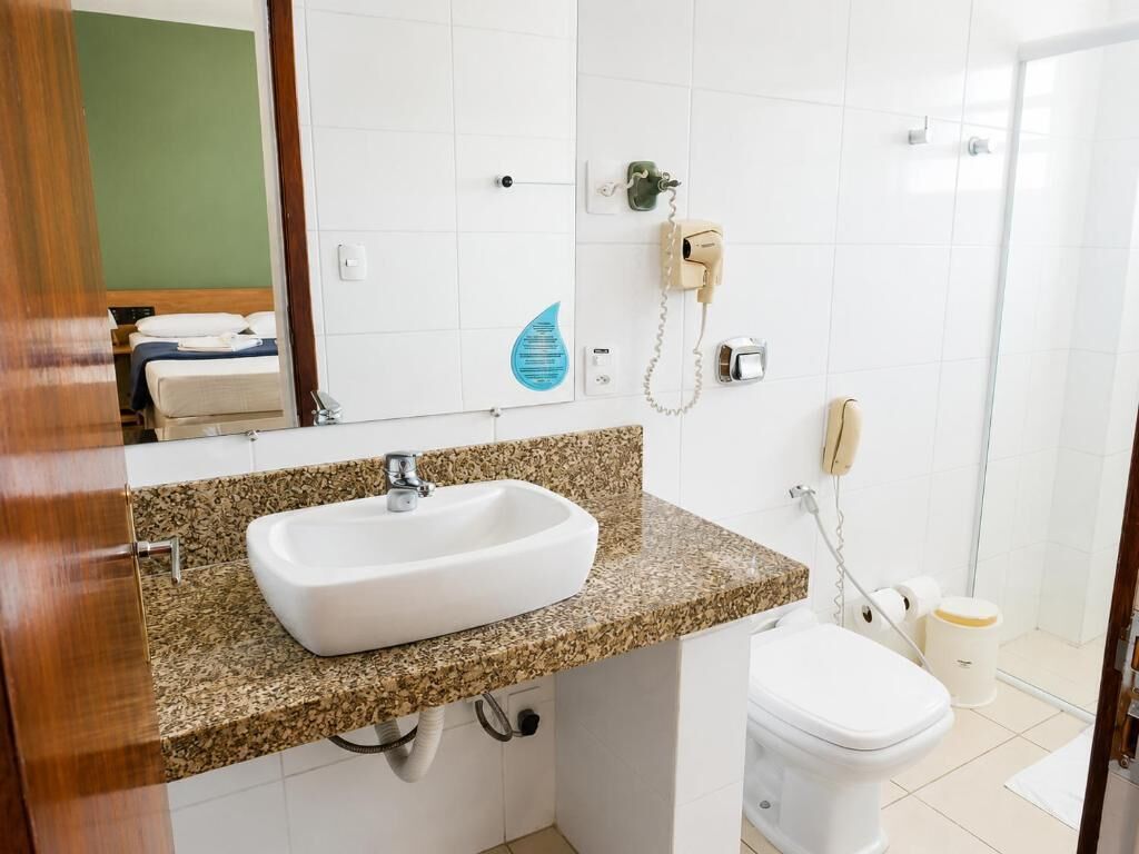 Un baño con lavamanos blanco, inodoro y zona de ducha.