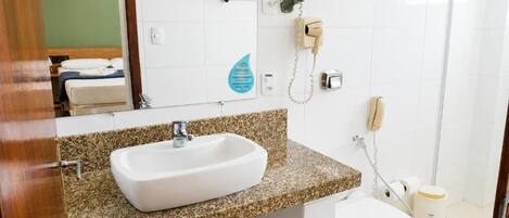 Un baño con lavamanos blanco, inodoro y zona de ducha.
