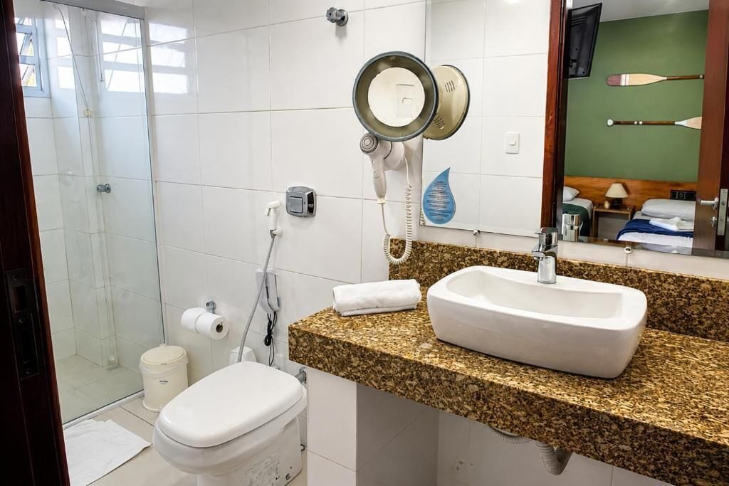 A bathroom with a shower, toilet, and a sink with a granite countertop.