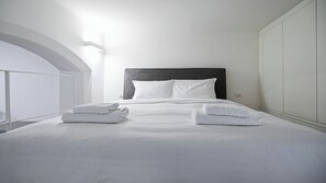 A neatly made bed with white linens and towels, a dark headboard, and a white wall with a light switch. - Italianway Collection - San Marco 14 (Milan)