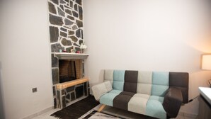 A living room with a stone fireplace, a sofa, and a rug. - Persefoni s Village House in Messara (Gortyna)