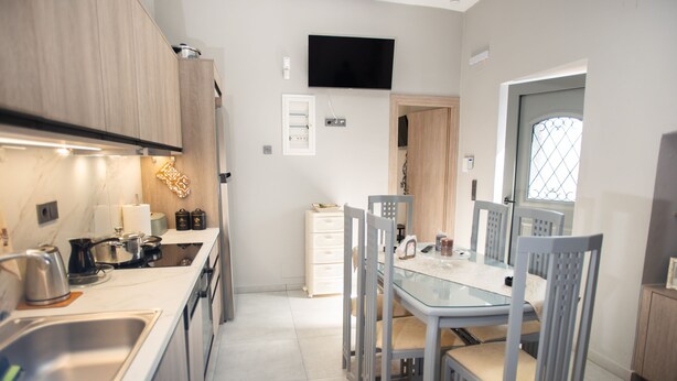 A modern kitchen with a dining area, built-in appliances, and a flat-screen TV. - Persefoni s Village House in Messara (Gortyna)