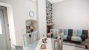 A dining area with a glass table, chairs, a clock, and a stone wall. - Persefoni s Village House in Messara (Gortyna)