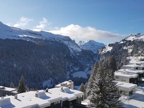 Eine verschneite Berglandschaft mit einem Tal und einer Reihe moderner Gebäude mit flachen Dächern.
