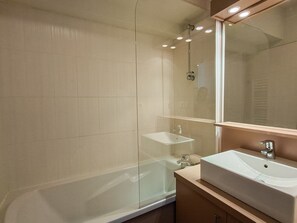Ein modernes Badezimmer mit einer Duschkabine, einer weißen Badewanne und einem großen Spiegel über einem Waschbecken.