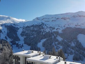 Eine verschneite Berglandschaft mit einem Gebäude, das ein flaches Dach und mehrere Schornsteine hat.