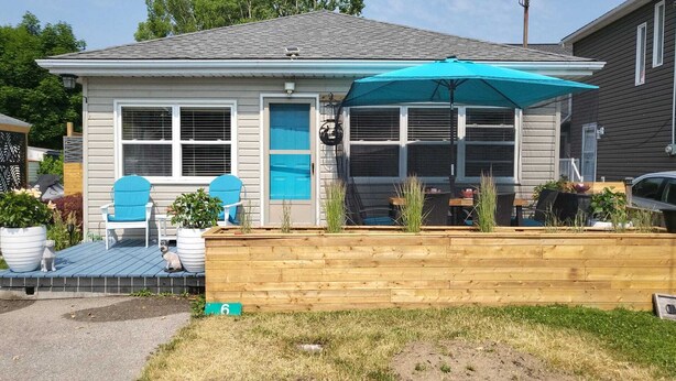 Ein Haus mit überdachter Terrasse, einem Hund und einer Holzterrasse.