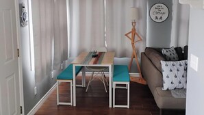 Ein Zimmer mit Esstisch, einer Couch, einem Deckenventilator und einem an der Wand befestigten Schild.