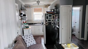 Ein Wohnzimmer mit einem braunen Sofa, einem schwarzen Hocker und einem Deckenventilator.