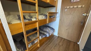 A bunk bed with three levels, a wooden door with a coat of arms, and a wooden floor. - Studio for 4 in Serre-Chevalier, Southeast Balcony (Saint-Chaffrey)