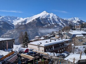 Eine Bergstadt mit schneebedeckten Gebäuden, einem Restaurant und Blick auf verschneite Berge.