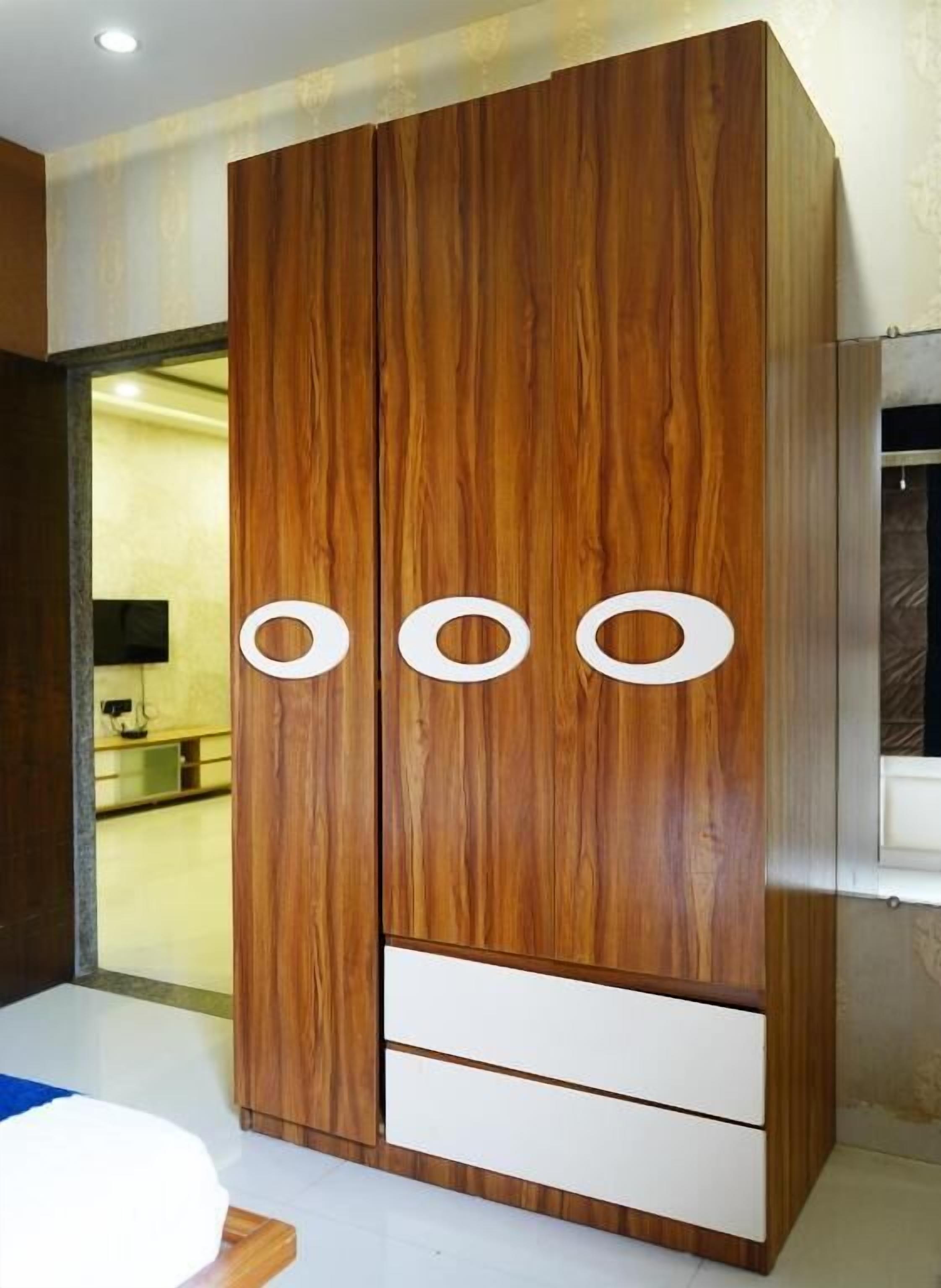 Une grande armoire en bois dotée de trois ouvertures circulaires et de deux tiroirs.