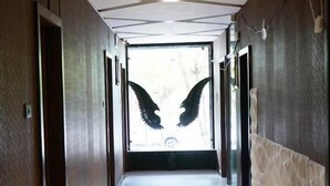 A hallway with a modern design, featuring a geometric ceiling pattern and a central door with a unique wing-like design. - Stay10 Luxury Service Apartment (Indore)