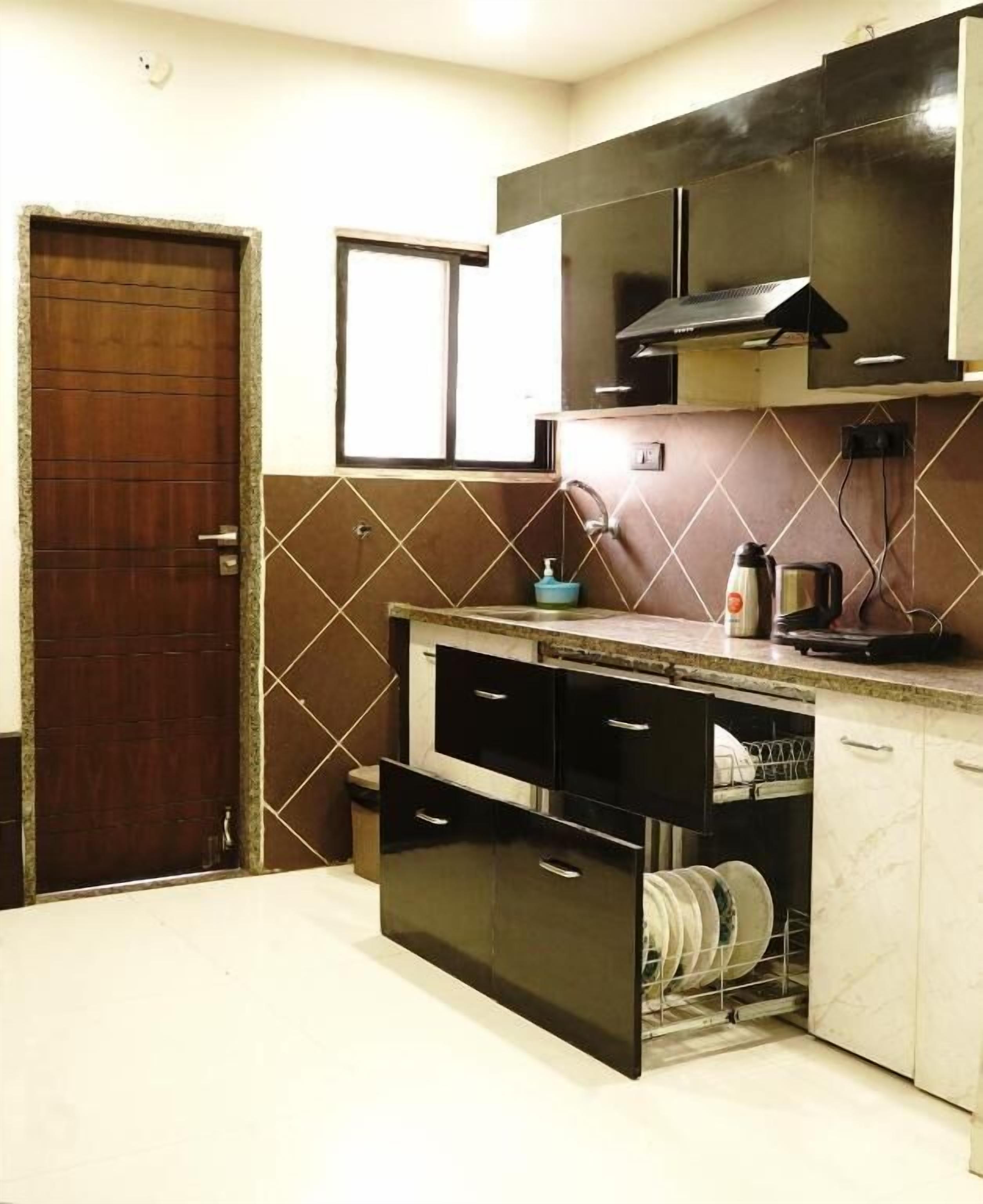 A kitchen with a wooden door, tiled backsplash, and a dishwasher.