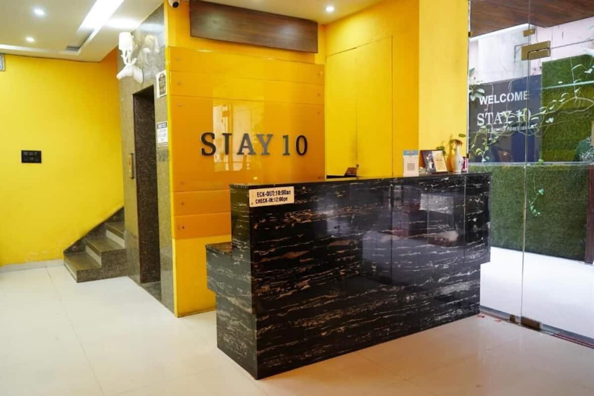Ein Empfangsschalter mit einem 'STAY 10' Schild, einer Glastrennwand und einem 'WELCOME STAY HOME' Schild.