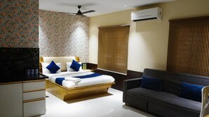 A hotel room with a bed, a sofa, a desk, and an air conditioning unit. - Stay10 Luxury Service Apartment (Indore)