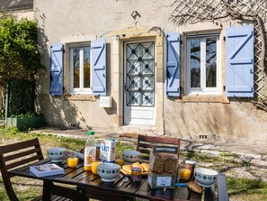 A table set outdoors with breakfast items, a house with blue shutters, and a door with a window. - House in bastide, pets allowed - 5 guests (MONTFAUCON)