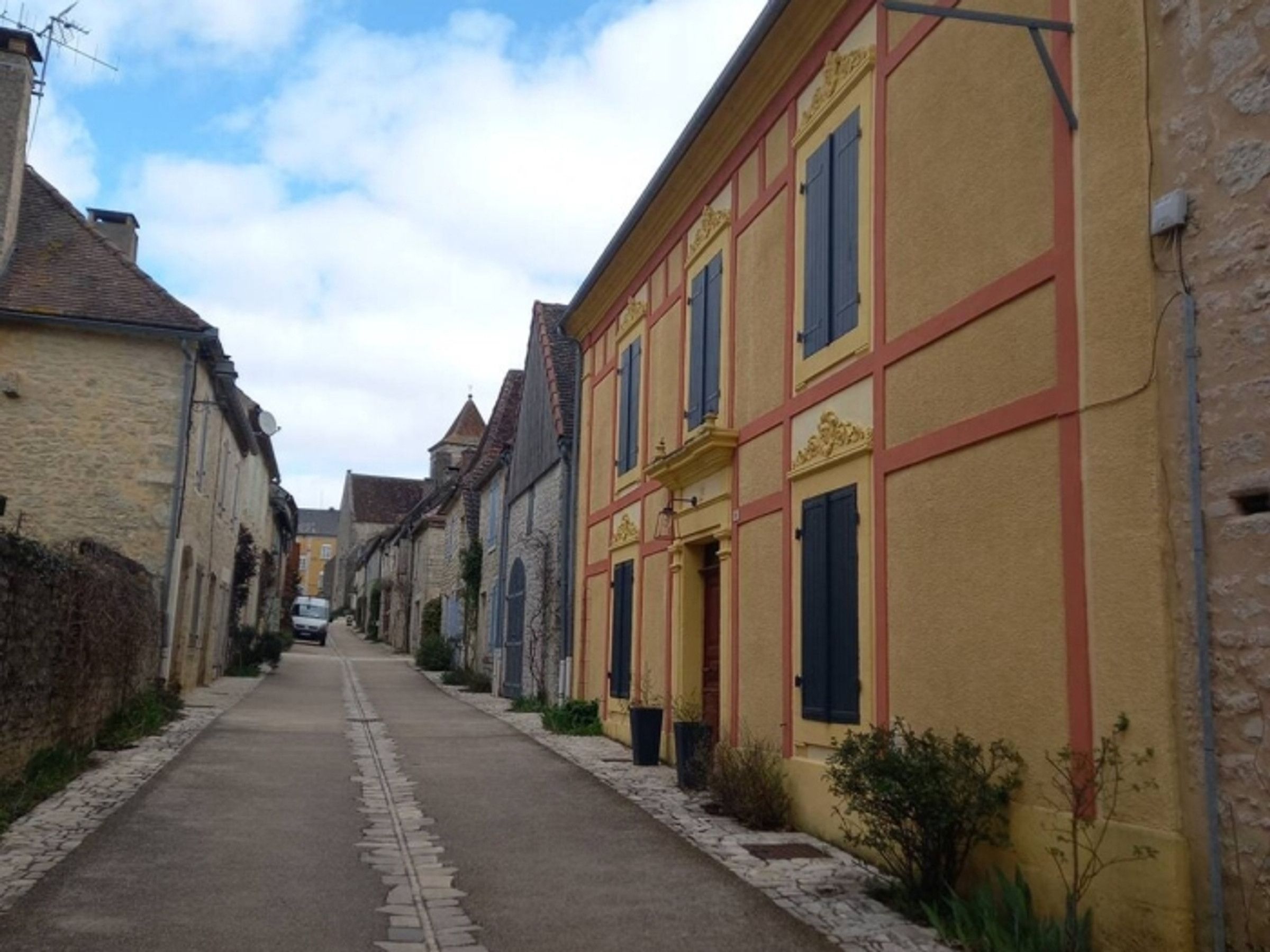 A narrow street lined with traditional buildings, some with visible signage, and a clear sky above.