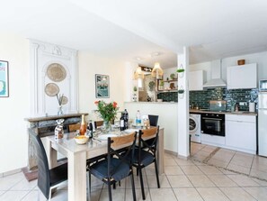 A modern kitchen with white cabinets, a dining area with a wooden table and chairs, and a built-in oven.
