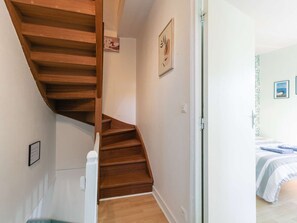 Una escalera de madera que lleva a un dormitorio con una cama y un cuadro en la pared.