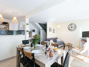 Un apartament modern amb zona de menjador, cuina, sala d'estar i una escala.