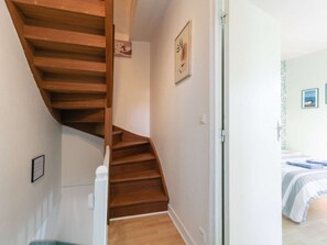 Eine Holztreppe führt zu einem Schlafzimmer mit einem Bett und einem Fenster.