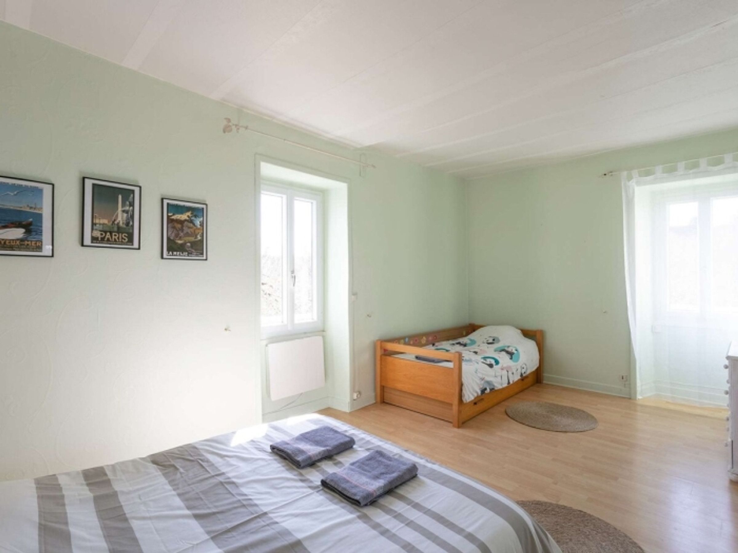 Une chambre à coucher avec un lit, une fenêtre et des œuvres d’art mural.