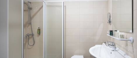 A bathroom with a shower, toilet, sink, and mirror.