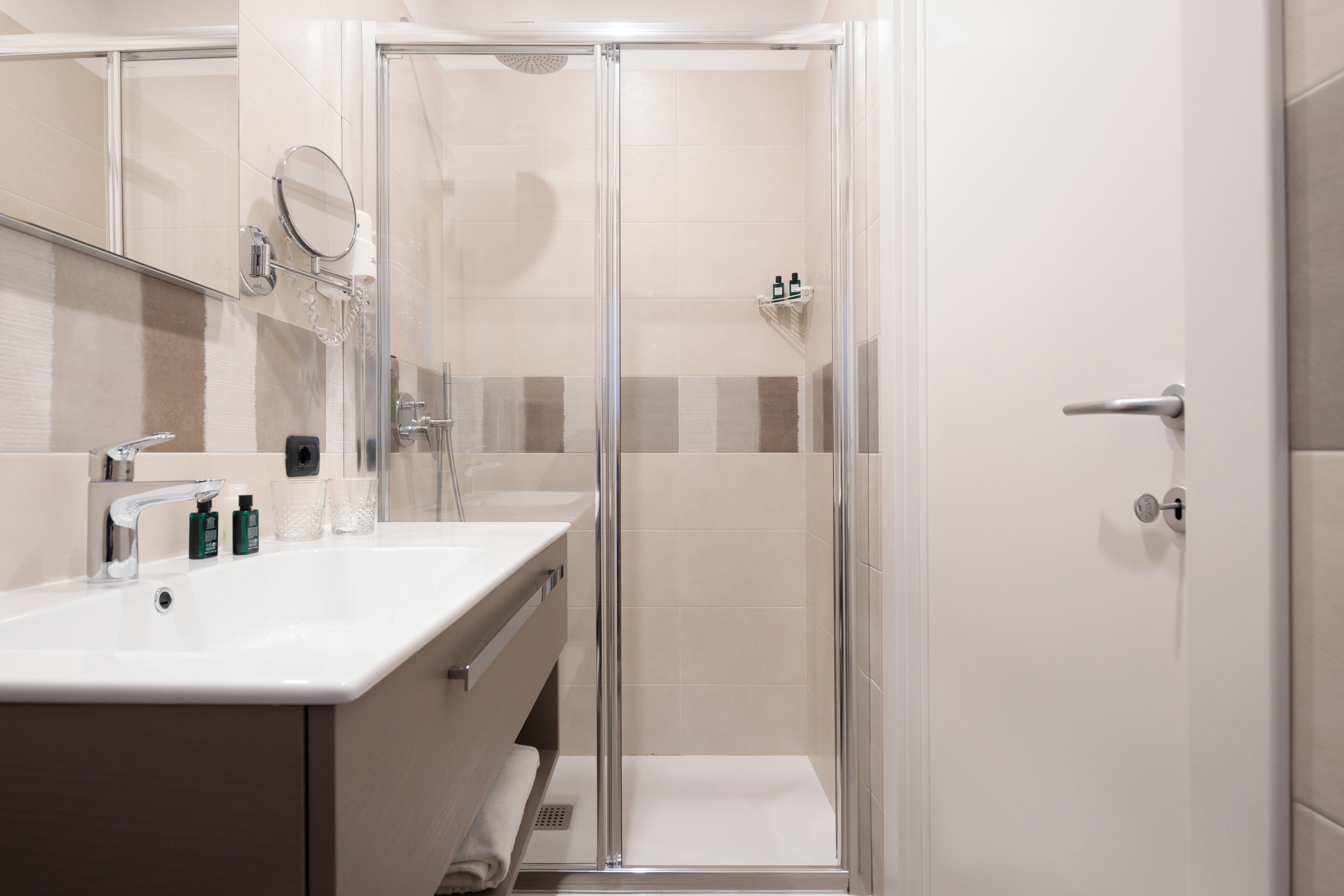 A modern bathroom with a glass-enclosed shower, a white sink with a mirror, and a towel rack.