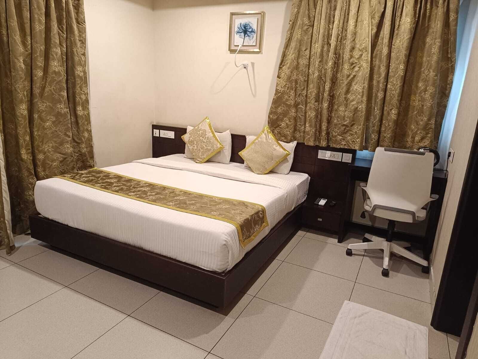 Una habitación de hotel con una cama, dos mesitas de noche, una silla y un cuadro en la pared.