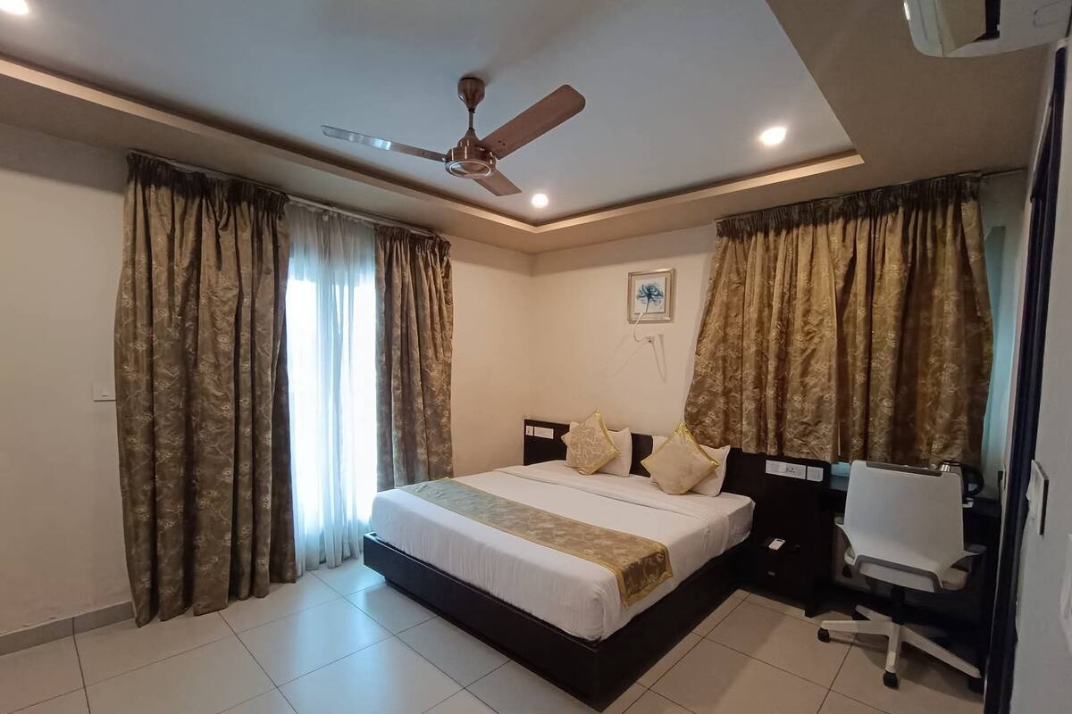 Un dormitorio con cama, cortinas, ventilador de techo y escritorio con silla.