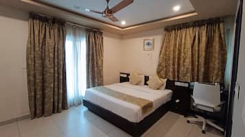 A bedroom with a bed, curtains, a ceiling fan, and a desk with a chair.