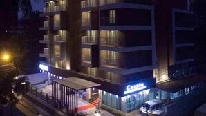 A multi-story hotel with balconies, a covered entrance, and a visible restaurant named 'Cassis.' - Casa In Luxury Suites (Thiruvananthapuram)