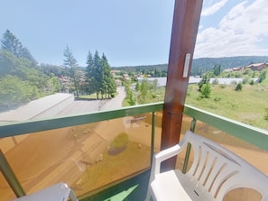 Ein Balkon mit Blick auf ein Wohngebiet, ein Holzpfosten und ein weißer Plastikstuhl.