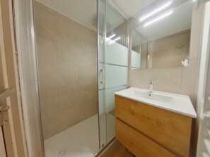 A modern bathroom with a glass shower enclosure, a white sink, and a wooden vanity. - Apartment in Prémanon center - 6 guests (Prémanon)