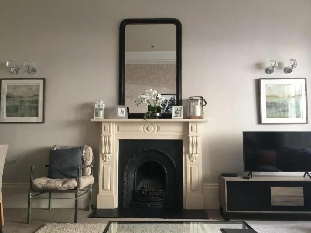 A living room with a fireplace, a television, and framed artwork on the walls.