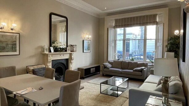 Ein geräumiges Wohnzimmer mit Kamin, einer Sofagarnitur, einem Essbereich und einem großen Fenster mit Blick auf die Stadt.