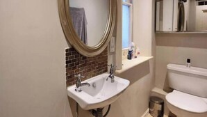 Ein Badezimmer mit Waschbecken, Spiegel, Toilette und Fenster.