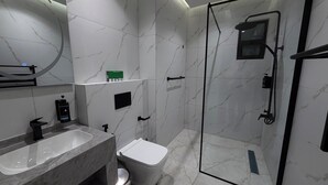 Un bagno moderno con lavabo, water e doccia in marmo.