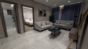 Un soggiorno moderno con un divano, un tavolino e un letto nella stanza adiacente.