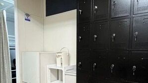 A room with a white refrigerator, a white shelf unit, and a black storage cabinet with multiple locks. - Tengcle Stay - Hostel (Tokyo)