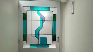 A hallway with a door featuring a geometric stained glass design. - Tengcle Stay - Hostel (Tokyo)