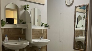 Un baño con dos lavamanos, un reloj y un cuadro en la pared.