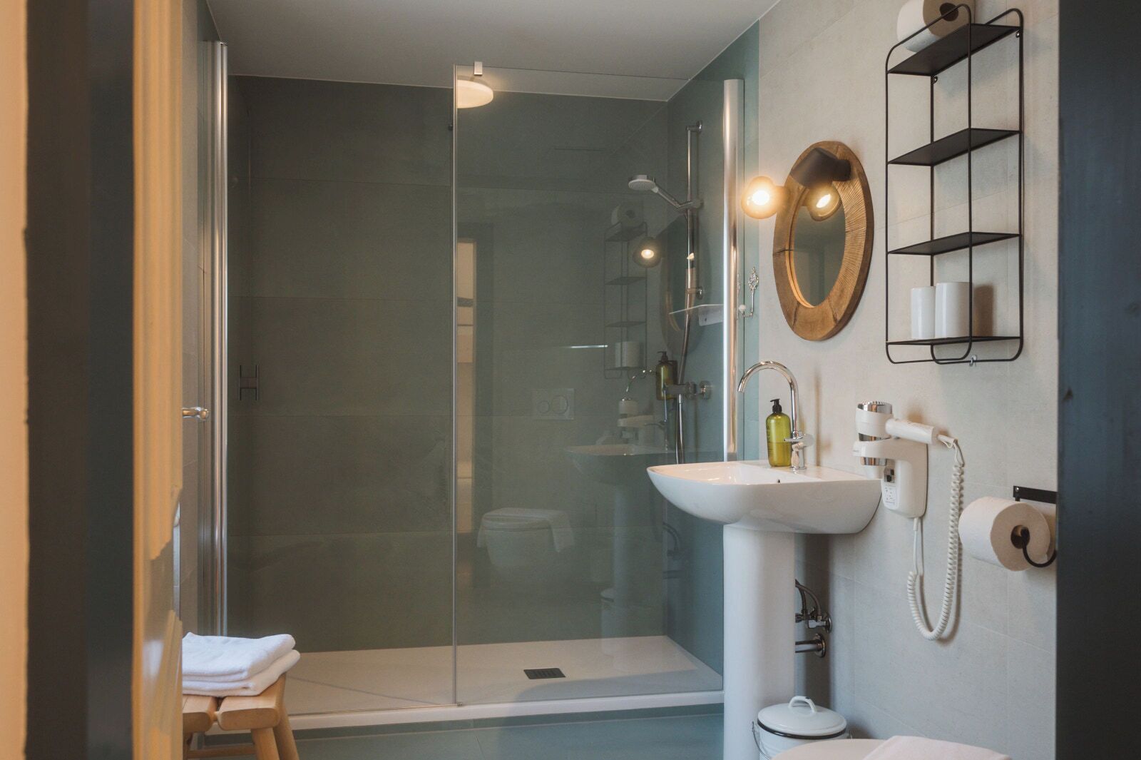 A modern bathroom with a glass-enclosed shower, a white sink, a mirror, and a toilet.